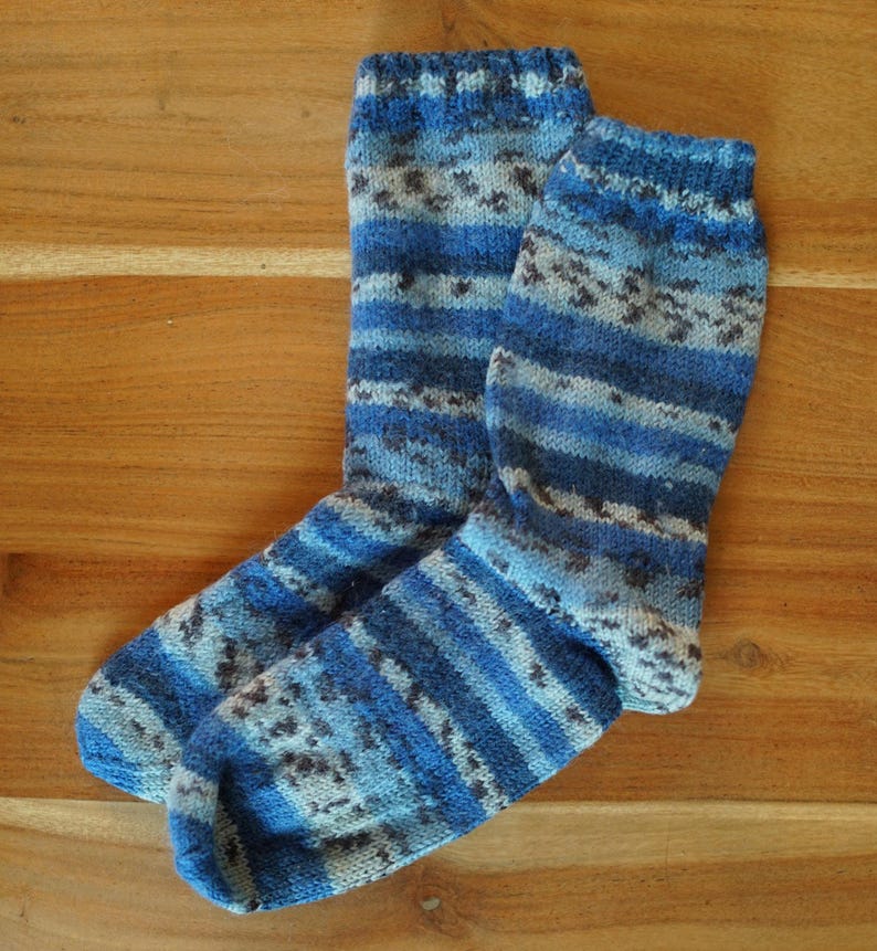 Pode incluir: Um par de meias de malha em tons de azul, cinza e branco. As meias apresentam um padr&atilde;o listrado e salpicado, com punho e calcanhar canelados. As meias s&atilde;o feitas de um material macio e quente.