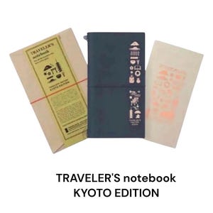 Könnte beinhalten: Ein dunkelblaues Traveler's Notebook Kyoto Edition mit passendem Papiereinsatz und einer Kraftpapierhülle. Das Notizbuch hat dekorative Symbole und Text. Die Kraftpapierhülle ist mit einem roten Faden umwickelt.