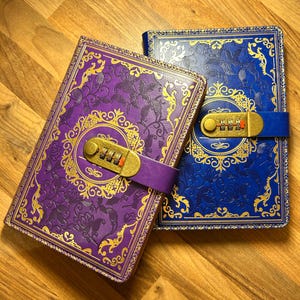 May include: Two decorative journals with combination locks. One journal is purple with gold accents, the other is blue with gold accents. Both have ornate floral designs and a strap to secure the lock.
