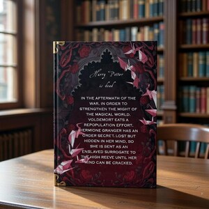 May include: A hardback book titled "Harry Potter is dead" with a dark red cover featuring floral and geometric patterns, and gold corner detailing. The book rests on a wooden table, set against a library backdrop.