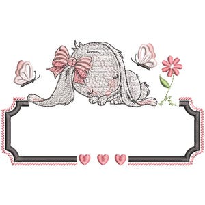 May include: An embroidered design featuring a sleeping bunny with a pink bow, butterflies, and a flower. The design includes a rectangular frame with three pink hearts at the bottom, ideal for personalization.