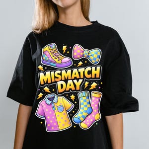 Può includere: T-shirt nero con grafica colorata "Mismatch Day". Il design include una sneaker alta, un papillon, una polo e calzini, ognuno con un motivo e una combinazione di colori unici. Il testo "Mismatch Day" è giallo.