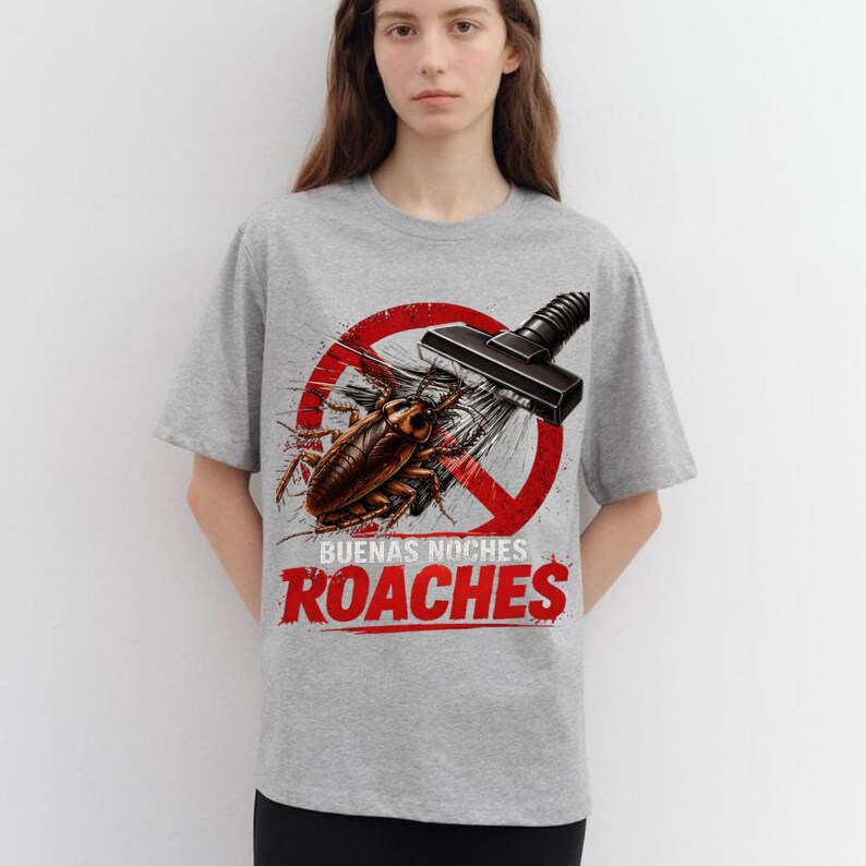 May include: Gray t-shirt featuring a graphic of a cockroach being vacuumed, with a red prohibition sign and the words "Buenas Noches Roaches" in red. The shirt is a light gray color.