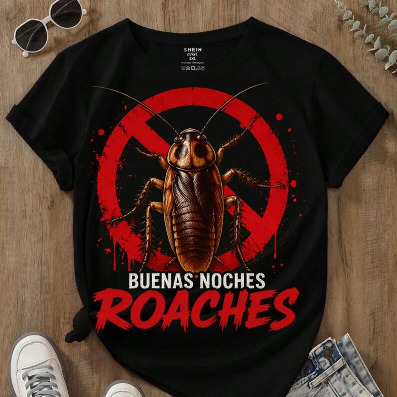 May include: Black t-shirt featuring a large, detailed cockroach illustration inside a red prohibition symbol. The words "BUENAS NOCHES ROACHES" are printed in red below the graphic. The shirt has short sleeves and a crew neck.