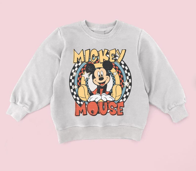 May include: A light grey sweatshirt with a retro Mickey Mouse graphic. The design features the words "Mickey Mouse" in yellow and red, with Mickey in the centre. The graphic is set against a checkered and star-filled background.