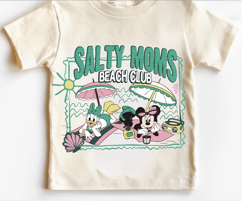 May include: Cream-colored t-shirt featuring the text "SALTY MOMS BEACH CLUB" in green. The graphic includes cartoon characters Daisy Duck and Minnie Mouse relaxing on the beach under umbrellas, with a boombox and seashell.
