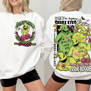 May include: White sweatshirt featuring a graphic of Oogie Boogie from The Nightmare Before Christmas. The front design includes the text "Well Well Well, What Have We Here?" The back features Oogie Boogie and the text "Snake Eyes Casino."