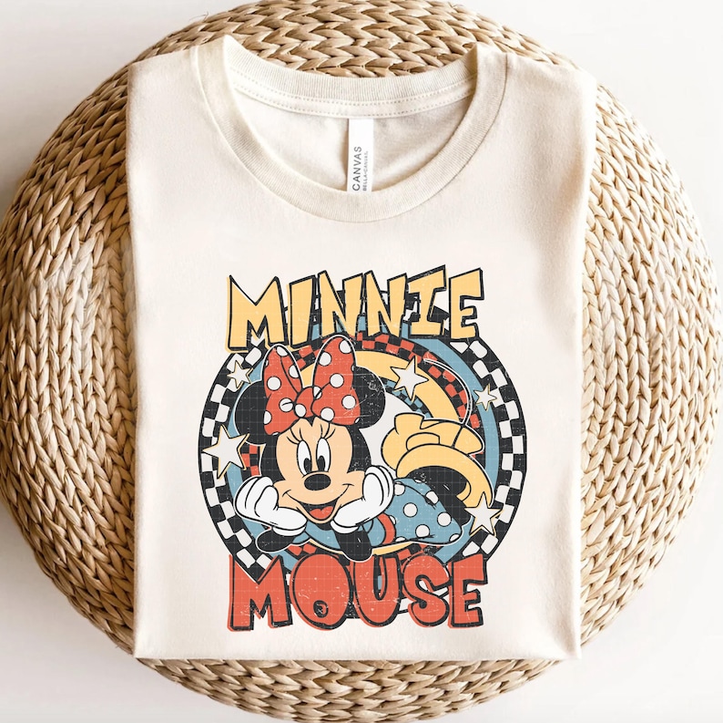 Puede incluir: Camiseta color crema con un gr&aacute;fico retro de Minnie Mouse. El dise&ntilde;o incluye la cara de Minnie, un lazo rojo con lunares y las palabras "MINNIE MOUSE" en una fuente vintage. La camiseta est&aacute; hecha de un material suave.