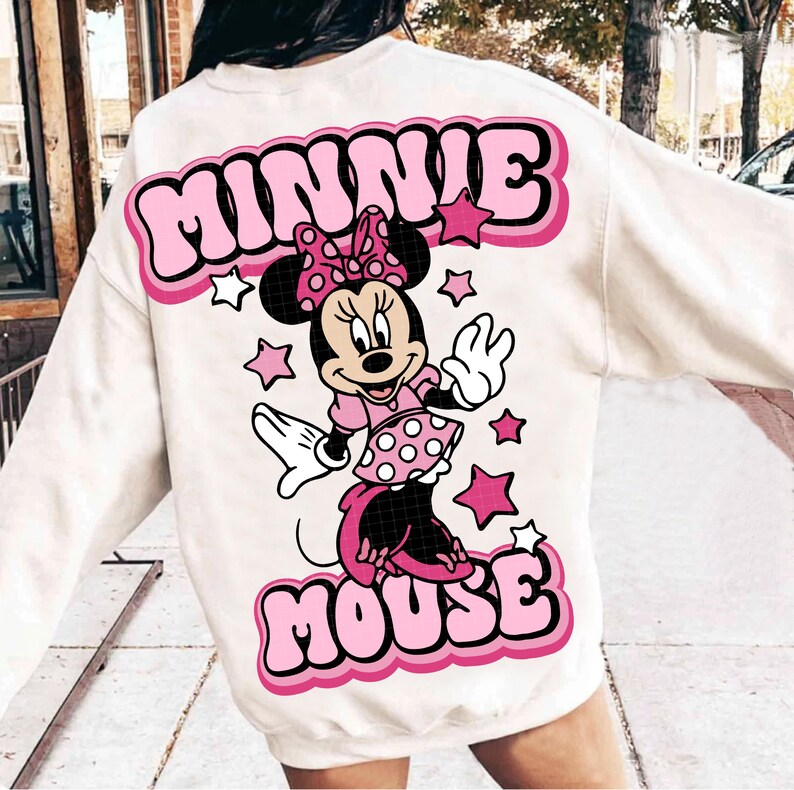Peut inclure: Sweat-shirt cr&egrave;me avec un motif Minnie Mouse. Le design comprend les mots "MINNIE MOUSE" en lettres roses, une image de dessin anim&eacute; de Minnie Mouse et des &eacute;toiles roses. Le sweat-shirt est de style d&eacute;contract&eacute;.