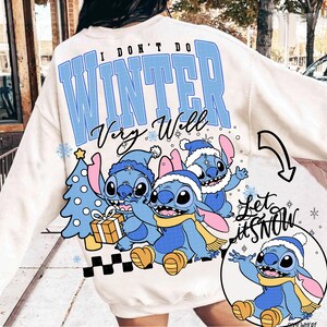 May include: Cream-colored sweatshirt with the text "I DON'T DO WINTER Very Well" in blue. Features a graphic of three blue cartoon characters wearing winter hats and scarves, with a Christmas tree and the words "Let it Snow".