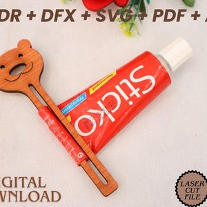May include: A wooden bear-shaped craft stick and a red tube of Sticko permanent transparent glue. The craft stick has a bear face design and the words "DIGITAL DOWNLOAD" are at the bottom. The image also includes the text "CDR + DFX + SVG + PDF + AI" and "LASER CUT FILE".