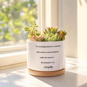 May include: A white ceramic planter with a wooden base, filled with various succulents. The planter has the quote "To everything there is a season, and a time to every purpose under the heaven." and the name "Golightly".