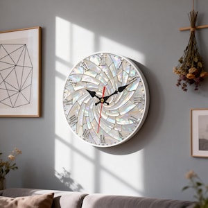 May include: A round wall clock with a white frame and a mother-of-pearl face. The clock features black hands, Roman numerals, and a red second hand. The clock is mounted on a light gray wall.