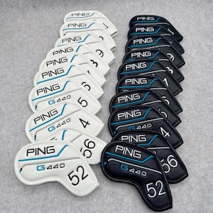 Puede incluir: Juego de fundas para palos de golf con el logotipo "PING" y la designación del modelo "G440". Las fundas son blancas y negras, con detalles en azul y numeradas del 1 al 6, y 52 y 56.