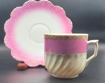Taza y platillo con diseño de bigote rosa y blanco.