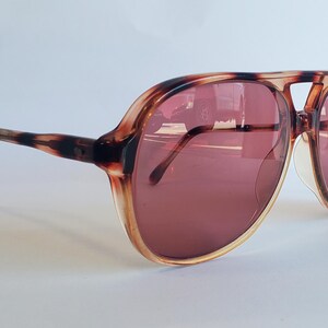 May include: Tortoise shell aviator sunglasses with brown tinted lenses.