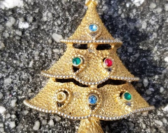 May include: A gold-tone Christmas tree brooch with red, green and blue rhinestones.