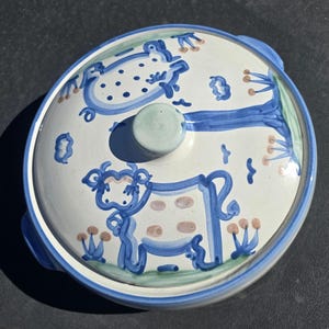 May include: A rustic wooden sign with the text "Welcome" in a handwritten style. The sign is painted white with a distressed finish, and features a decorative floral element in the corner. The background is a blurred image of a wooden surface.