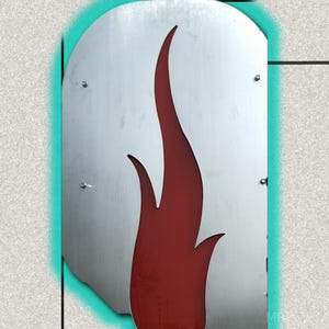 May include: A metal wall art piece featuring a stylized red flame design against a brushed silver background. The flame shape is cut out, revealing the wall behind it. The artwork is outlined with a teal border.