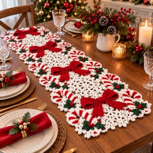 May include: A white crocheted table runner featuring a repeating pattern of snowflakes, red and white striped candy canes, and large red bows. The runner is decorated with small green holly leaves and red berries throughout the intricate design.