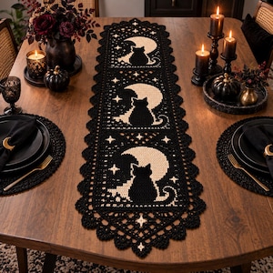 May include: A black and cream crochet table runner featuring a repeating pattern of a cat silhouette sitting in front of a crescent moon, accented with small star motifs and a scalloped, lacy border with a diamond-shaped lattice design.