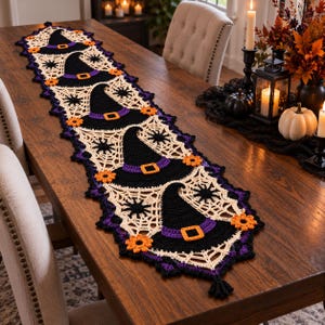 Peut inclure: Un long chemin de table en crochet rectangulaire présentant un motif répétitif de chapeaux de sorcière noirs avec des bandes violettes et des boucles orange, entremêlés de toiles d'araignée crème et de petites fleurs orange, bordé de violet foncé.