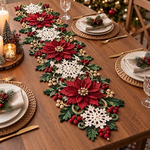 May include: A long, decorative crochet table runner featuring a repeating pattern of large red poinsettia flowers, white snowflakes, green holly leaves, and clusters of small red berries. The runner is centered on a wooden dining table.