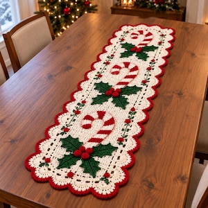 May include: A rectangular crochet table runner featuring an off-white base with a scalloped red border. The design includes three repeating motifs of red and white striped candy canes paired with dark green holly leaves and small red berries.