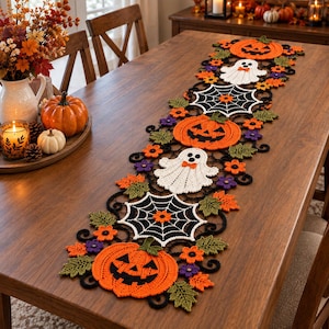 May include: A long, rectangular crochet table runner featuring a repeating pattern of orange jack-o'-lanterns, white ghosts with orange bow ties, black spiderwebs, and small purple and orange flowers with green leaves, all connected by black yarn.