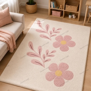 May include: Cream-colored rectangular rug with a floral design. The rug features two large pink flowers with yellow centers and pink leaf and stem accents. The rug is placed on a wooden floor.