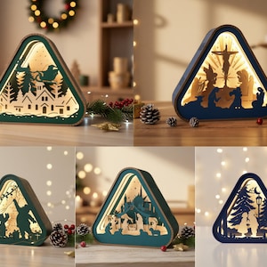 May include: A collection of five triangular wooden light boxes featuring intricate laser-cut silhouettes. Each piece displays a unique scene, including a winter village, a nativity scene, a holiday character, and a forest setting, all illuminated from within.