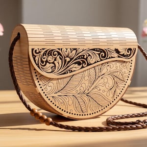 Peut inclure: Un sac à main en bois clair en forme de demi-lune. Le sac présente des sculptures florales et de feuilles complexes sur le rabat avant et le corps. Il a une bandoulière tressée marron et des perles en bois.
