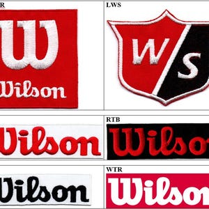 May include: A collection of six embroidered patches featuring the Wilson brand logo in various colour combinations. The designs include square, shield, and rectangular shapes with white, red, and black thread embroidery on fabric backgrounds.
