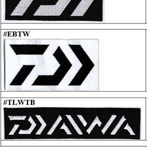 Puede incluir: Una colección de cuatro parches rectangulares bordados con el logotipo de Daiwa. Dos parches muestran la marca D estilizada en blanco sobre negro y negro sobre blanco, mientras que dos muestran el nombre de la marca Daiwa en blanco sobre negro y negro sobre blanco.