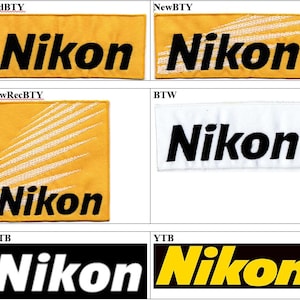 May include: A collection of six rectangular and square embroidered patches featuring the Nikon logo in various color combinations including yellow, black, and white. Some patches display the Nikon text with white diagonal line accents.
