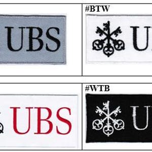 May include: Four rectangular embroidered patches featuring the UBS logo with three keys and the text UBS. The top left is gray with black embroidery, top right is white with black, bottom left is white with black keys and red text, bottom right is black with white.