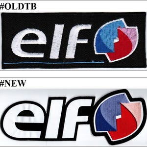 Peut inclure: Deux écussons brodés rectangulaires présentant le texte elf en lettres minuscules blanches. L'écusson du haut a un fond noir avec une ligne bleue et un logo en forme de bouclier bleu, rouge et blanc. Celui du bas a des lettres blanches à contour noir.