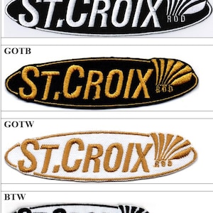 May include: Four oval-shaped embroidered patches featuring the text ST. CROIX ROD. The patches come in four color variations: white text on black, gold text on black, gold text on white, and black text on white, each with a fan-shaped graphic element.