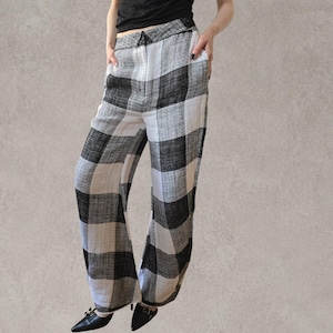 Puede incluir: Pantalones de talle alto con un llamativo estampado de cuadros en blanco y negro. Estos pantalones de pernera ancha est&aacute;n confeccionados en un tejido texturizado e incluyen una cintura estructurada con cremallera frontal y bolsillos laterales.
