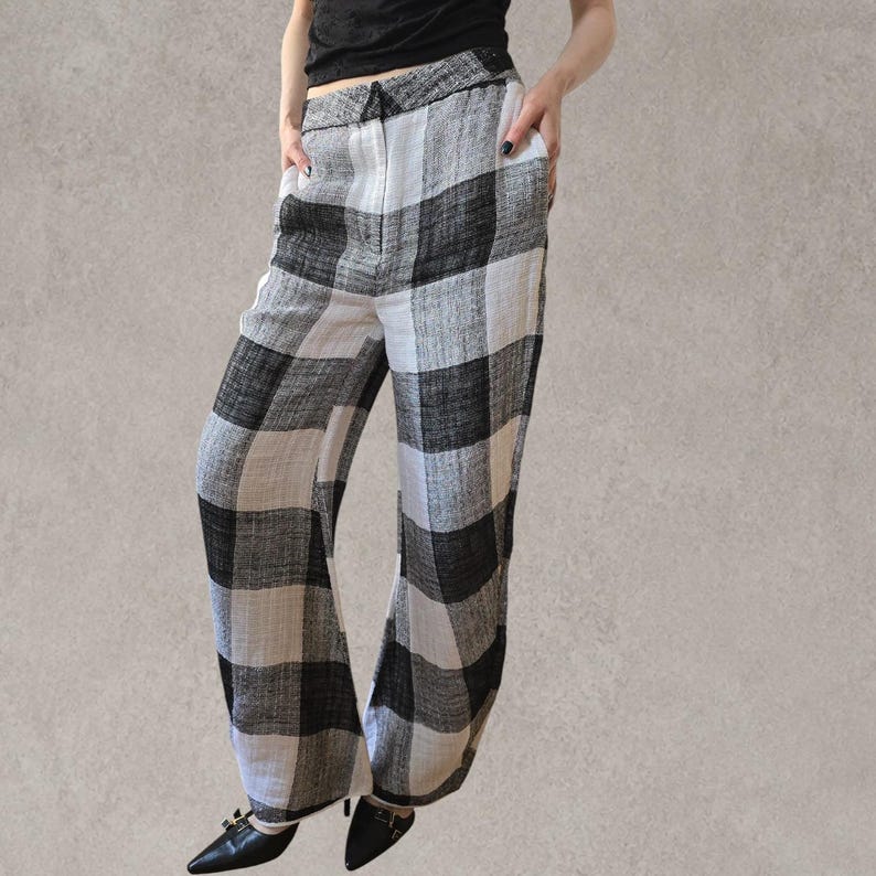 Puede incluir: Pantalones de talle alto con un llamativo estampado de cuadros en blanco y negro. Estos pantalones de pernera ancha est&aacute;n confeccionados en un tejido texturizado e incluyen una cintura estructurada con cremallera frontal y bolsillos laterales.