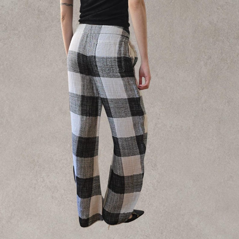 Puede incluir: Pantalones de largo completo con un patr&oacute;n de cuadros grandes en blanco y negro. Los pantalones tienen una silueta holgada de pierna ancha con un bolsillo trasero visible y un acabado de tela texturizada. La cintura es el&aacute;stica y c&oacute;moda.