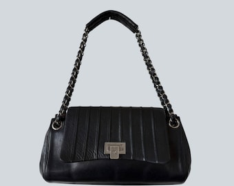 Bolso Chanel negro de piel acolchada vertical con solapa tipo acordeón.