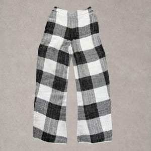 Puede incluir: Pantalones largos con un llamativo estampado de cuadros negros y blancos. Estos pantalones presentan una silueta de pierna ancha, una cintura alta el&aacute;stica y una costura vertical visible que recorre el centro de cada pierna para dar forma.