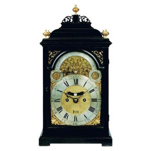 May include: A black antique clock with gold detailing. The clock face features Roman numerals and a gold centre. The clock is rectangular with decorative carvings and gold finials.