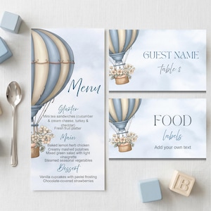 May include: A set of stationery with a hot air balloon design in blue and beige. The set includes a menu, guest name card, and food label. The menu lists starter, main, and dessert options. The guest name card says "table 8".