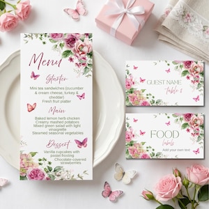 May include: A wedding stationery set featuring a menu, guest name cards, and food labels. The designs include floral arrangements with pink and purple flowers, butterflies, and elegant script. A gift box and napkins are also visible.