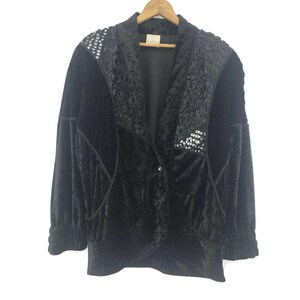May include: Black velvet blazer with decorative sequin and embroidered accents. The jacket features a notched collar and a single-button closure. The sleeves are gathered at the cuffs, and the blazer is hung on a wooden hanger.