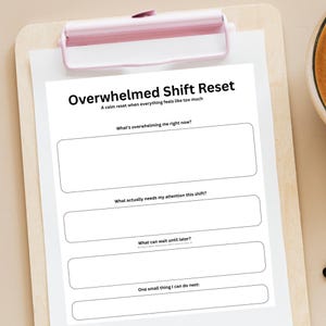 May include: A white clipboard with a pink clip holding a printed sheet titled "Overwhelmed Shift Reset." The sheet includes prompts for self-reflection, such as "What's overwhelming me right now?" and "One small thing I can do next:"