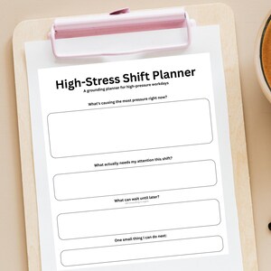 May include: A white High-Stress Shift Planner on a wooden clipboard with a pink clip. The planner has prompts for high-pressure workdays, including sections for identifying pressure sources and prioritizing tasks.