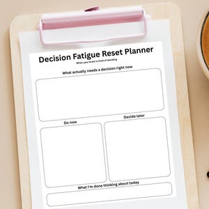 May include: A white Decision Fatigue Reset Planner on a wooden clipboard with a pink clip. The planner has sections labeled "What actually needs a decision right now", "Do now", "Decide later", and "What I'm done thinking about today".